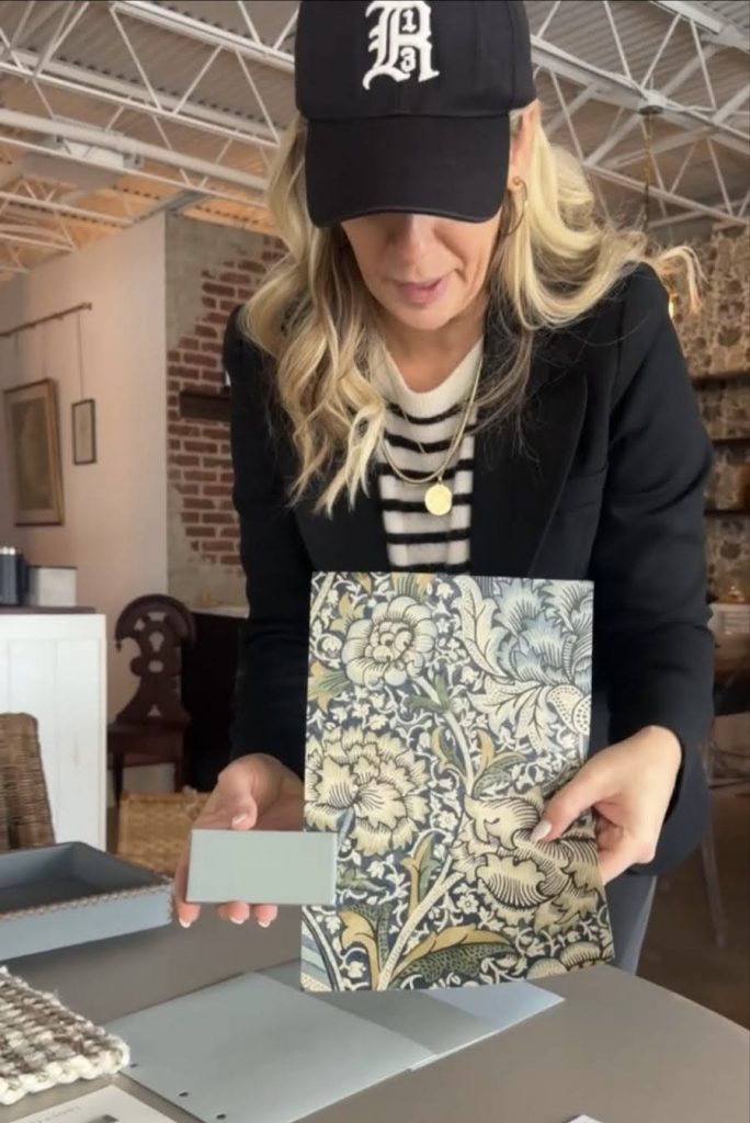 Amanda Chando selecting blue wallpaper and fabric swatches for an interior design project.